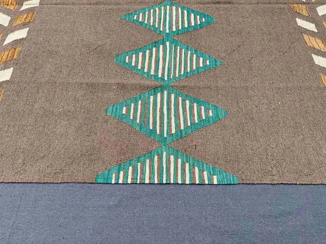 Close-up of weave texture on 6x9 Kilim rug in brown and turquoise wool.