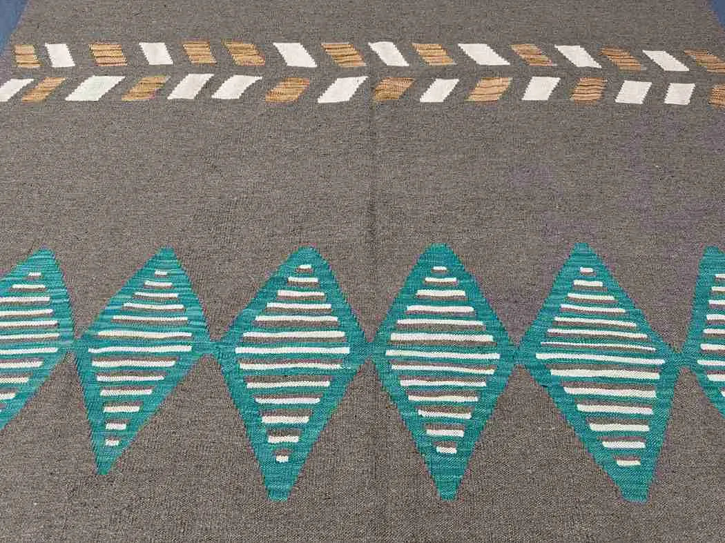 Close-up of weave texture on 6x9 Kilim rug in brown and turquoise wool.