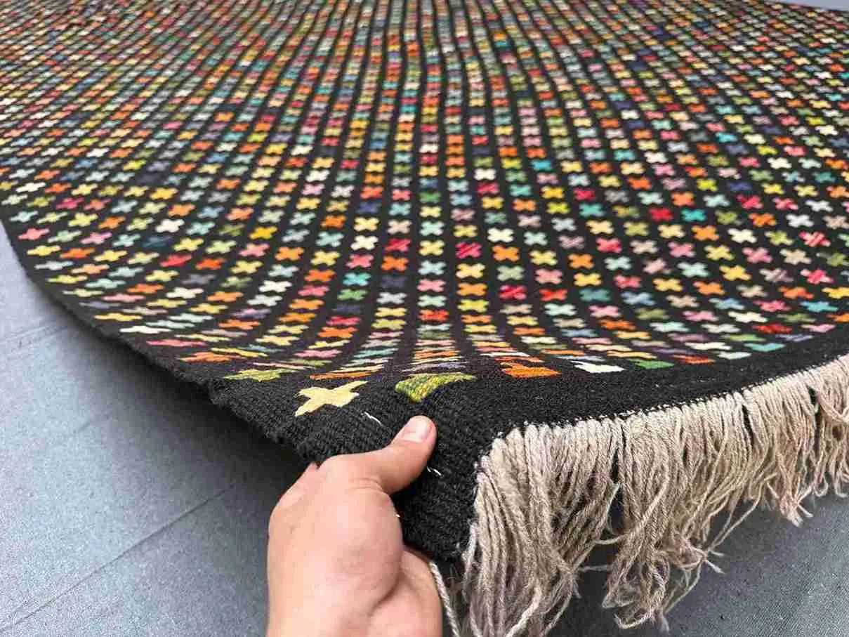 Front view of 8x12 colorful Turkish Kilim rug held in hands – multicolor geometric wool flatweave.