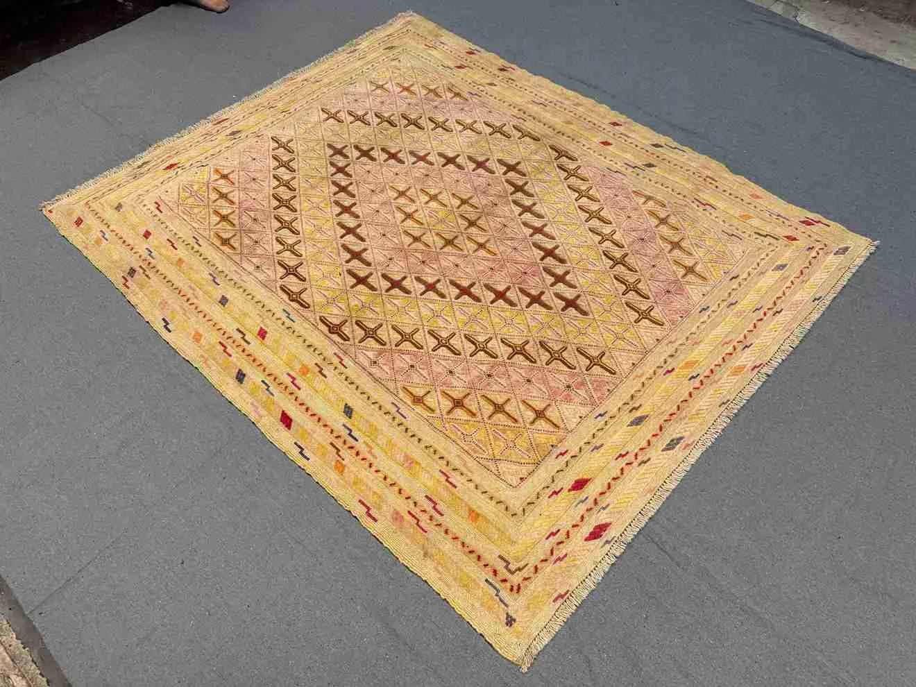 Soft pastel Afghan kilim rug styled on floor with boho decor