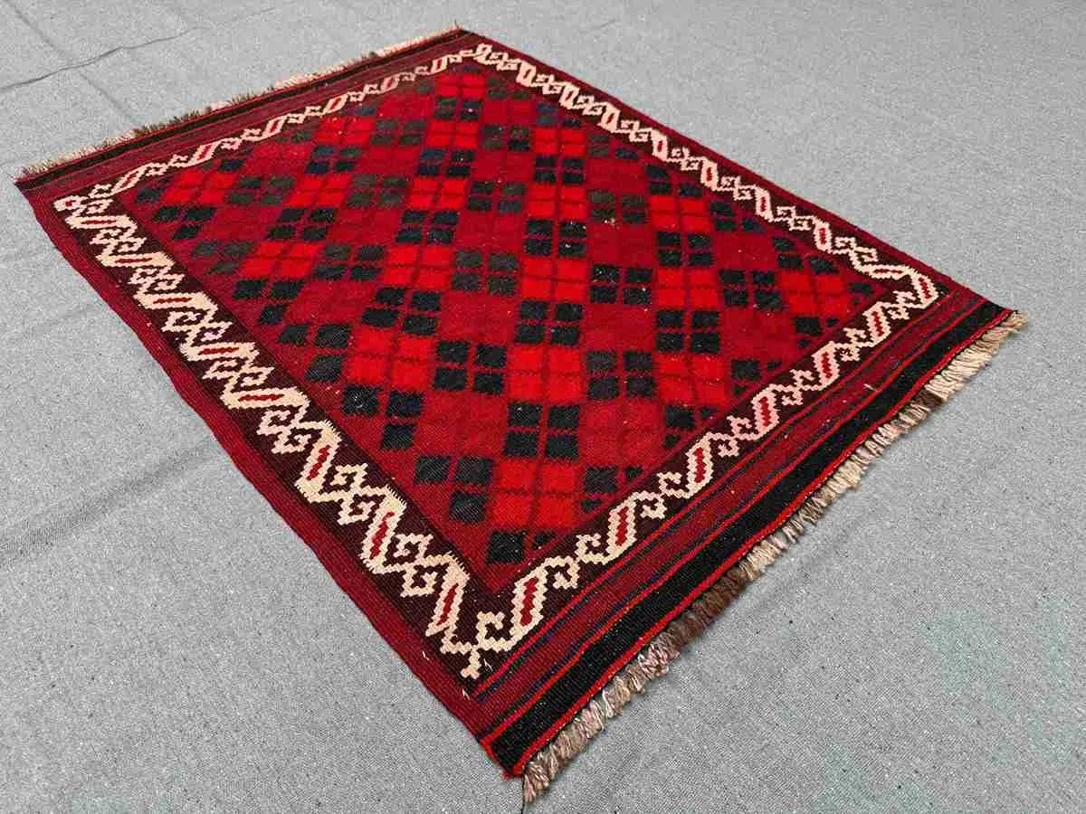 Small vintage Afghan Kilim rug displayed on floor – red wool flatweave for rustic or boho decor.