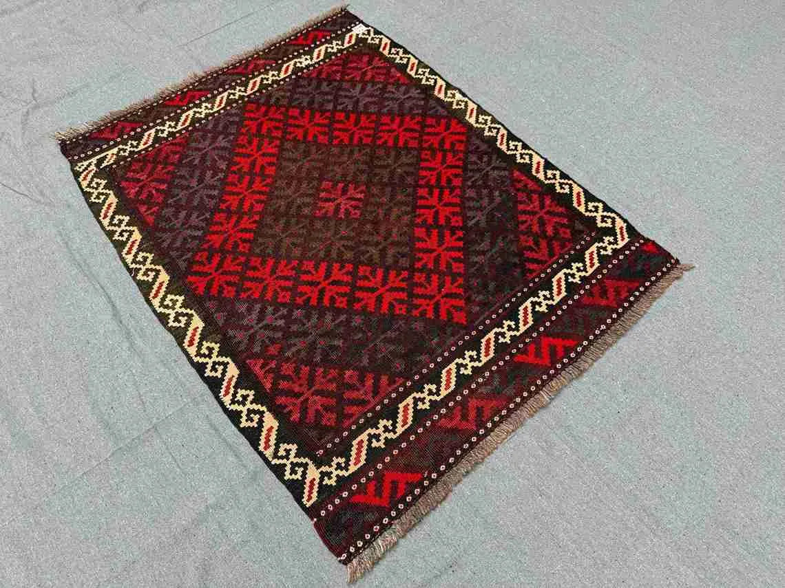 Small Afghan Kilim rug styled on wooden floor – vibrant red wool flatweave for home decor