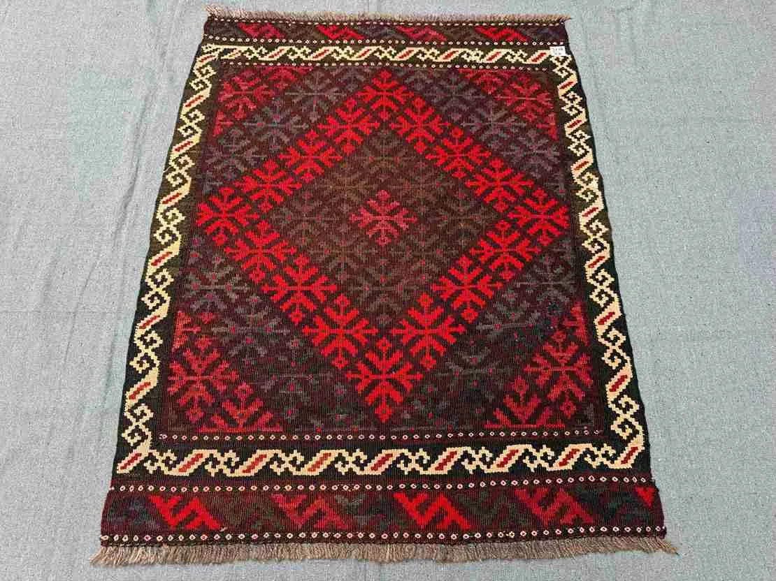 Floor scene with Afghan small Kilim flatweave – geometric design in red wool.