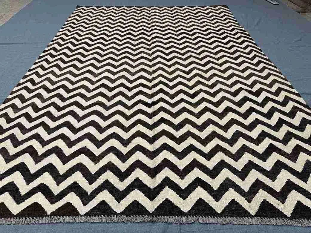 Full view of black and ivory handmade Kilim rug on wooden floor