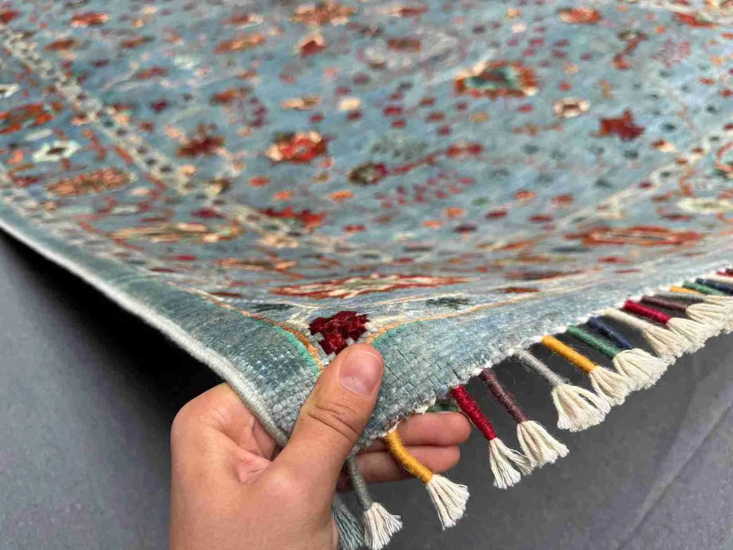 Hand showing the texture of 6x8 blue & gray oriental wool rug