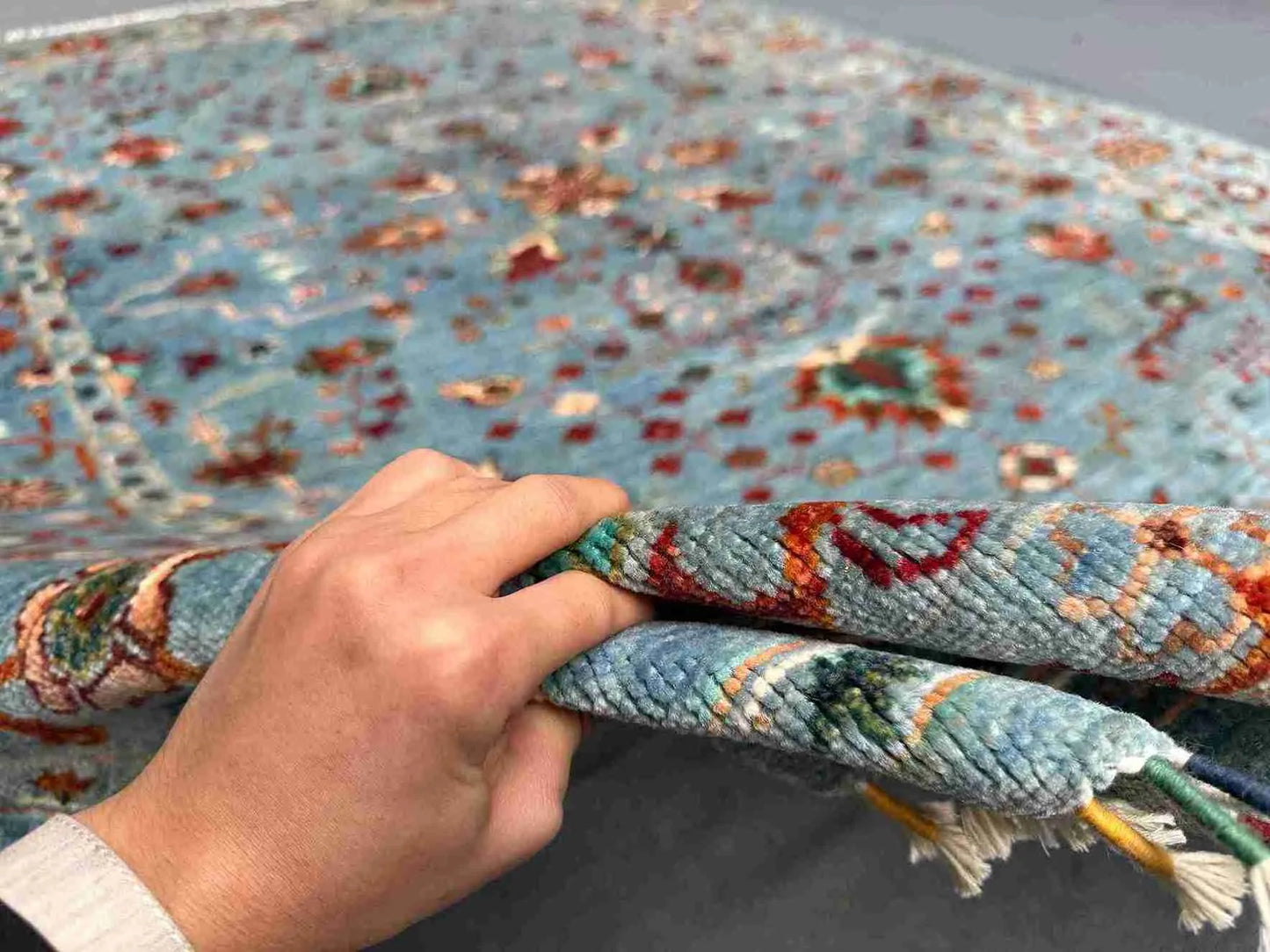 Detailed hand-held view of handmade floral wool carpet