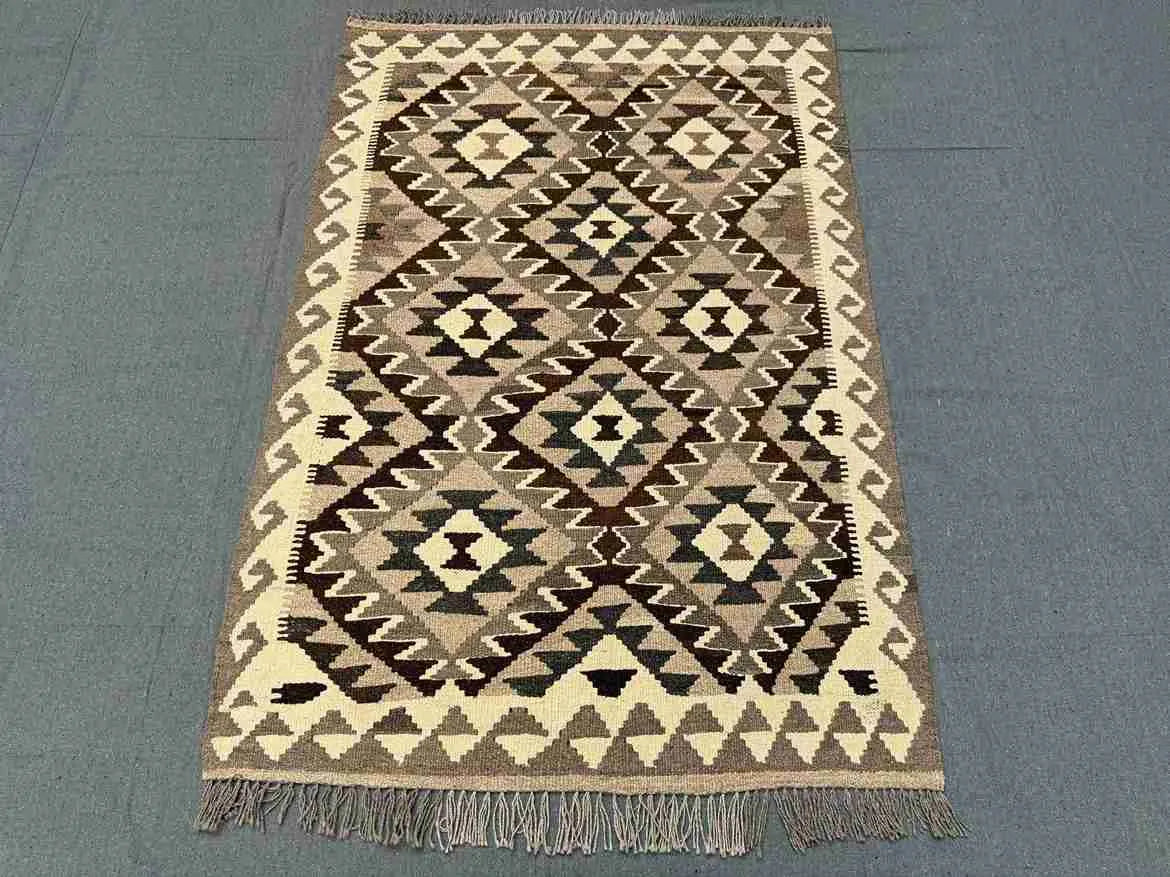 Boho-style small Kilim rug laid out on floor – wool handmade area rug for rustic or ethnic decor.