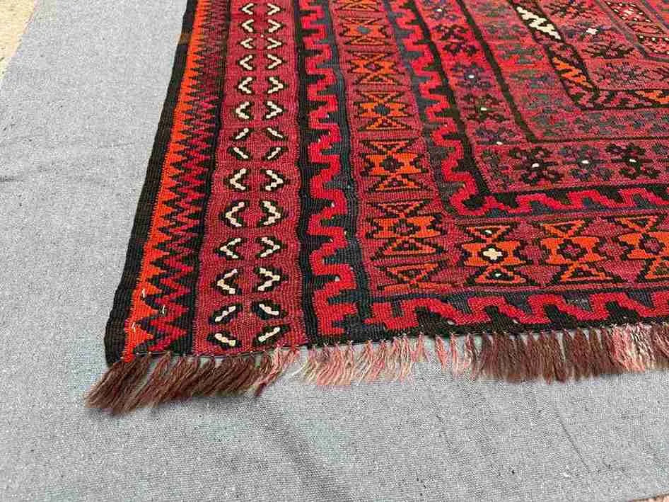 Corner detail of large 8x13 vintage Kilim rug – red and black geometric tribal wool flatweave.