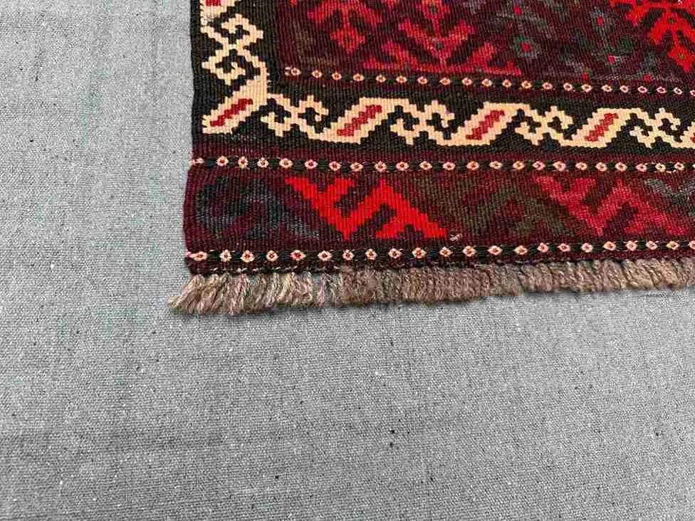 Corner detail of vintage Afghan Kilim rug – small red wool flatweave with knotted tribal accents.