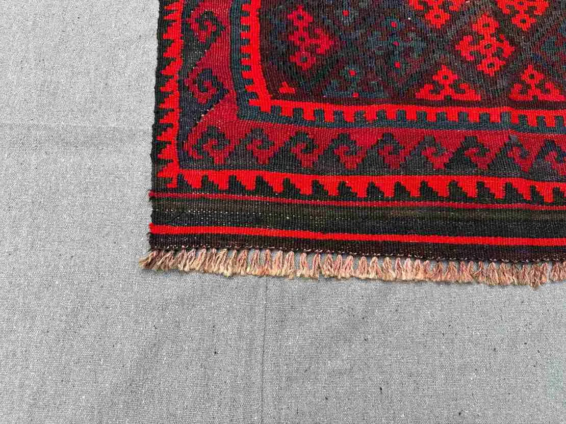 Corner detail of vintage small red Kilim rug – tribal geometric design with wool flatweave texture.