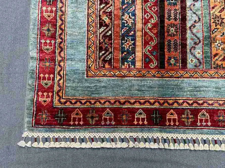 Corner view showing detailed stripe and floral motifs on wool Turkish rug