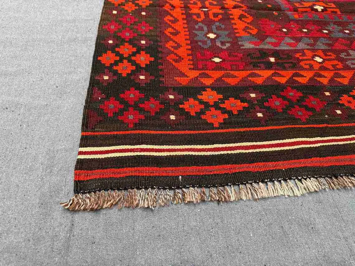 Corner detail of vintage red and black Turkish Kilim rug – tribal knotted wool flatweave.