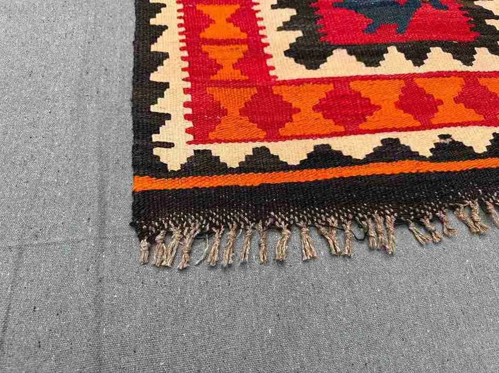 Corner detail of red and orange Turkish Kilim rug – handmade wool flatweave with tribal pattern.