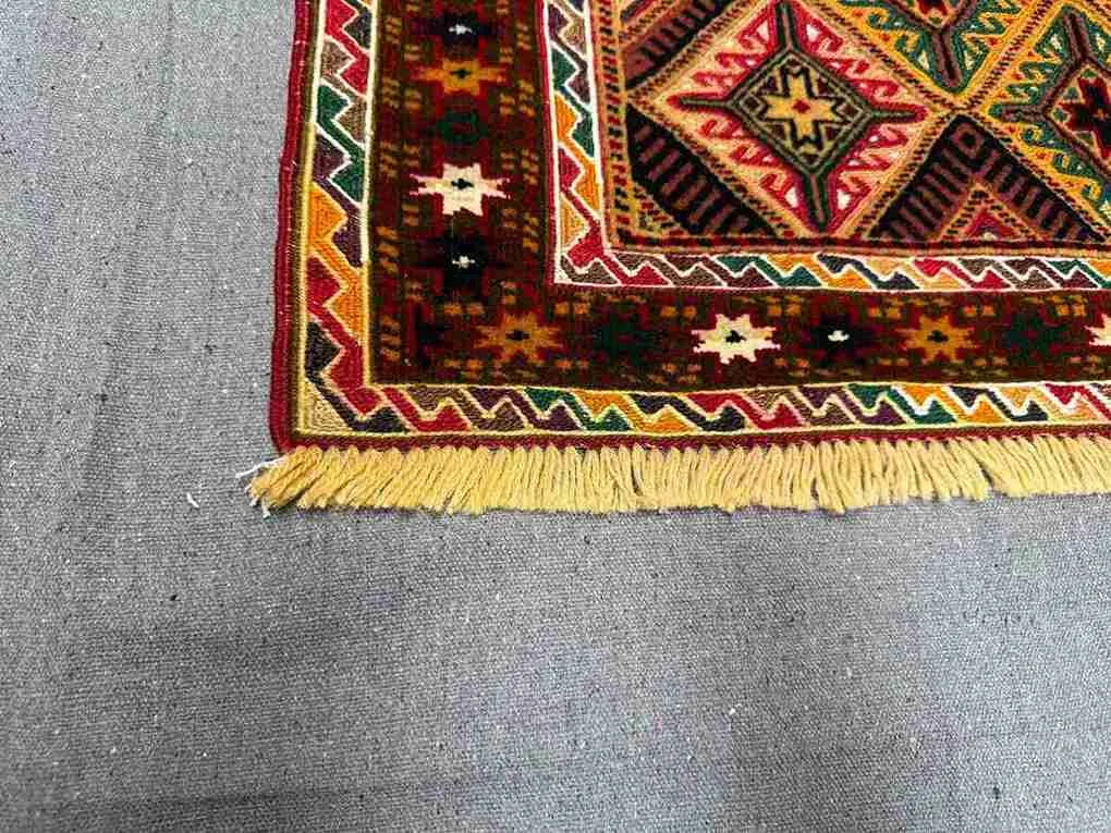 Corner detail of 2.5x4.3 wool kilim runner rug with red, green and gold tones