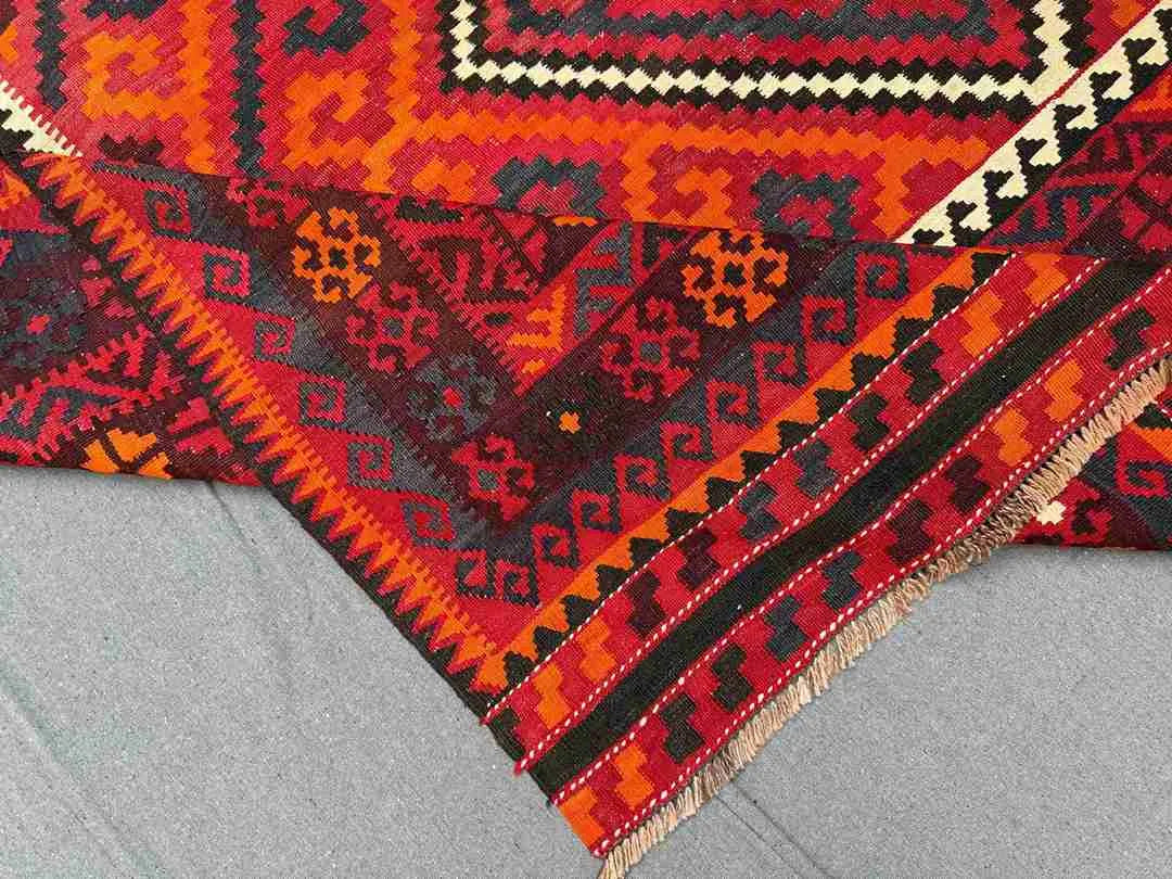 Folded view of 8x12 Turkish Kilim rug – vintage red and black tribal wool flatweave.