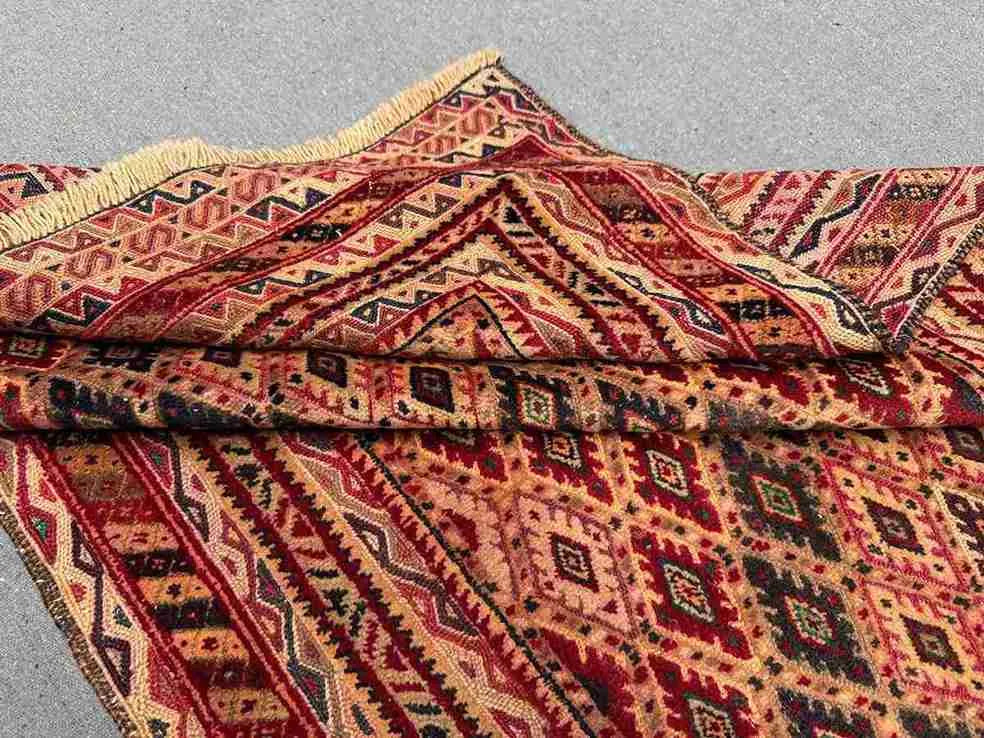 Side view of folded Persian Afghan rug showing wool thickness