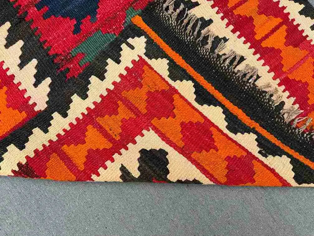 Folded view showing backside of multicolor Turkish Kilim rug – vintage hand-knotted wool.