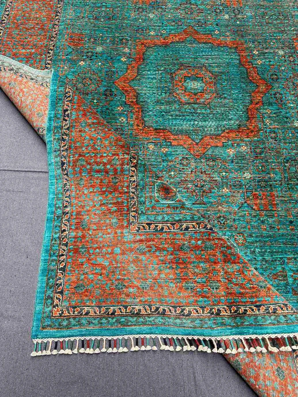 Folded handmade 6x8 Mamluk rug showing vibrant colors and texture