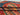 Handmade wool Afghan rug folded – showing red and green stripe pattern.