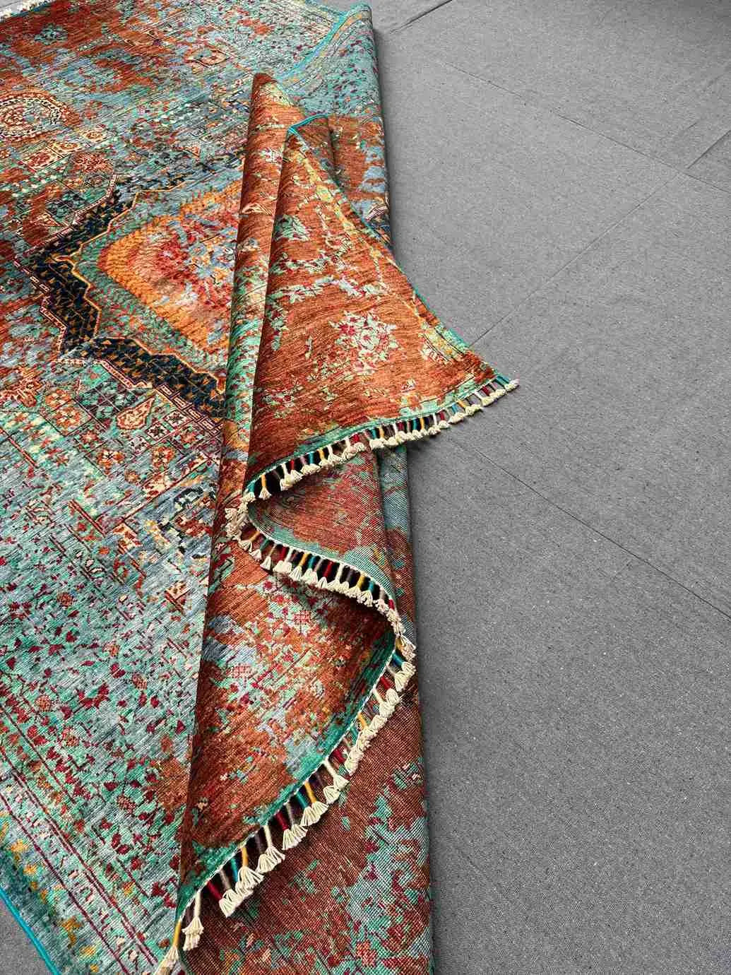 Folded view of blue, orange, and red Mamluk wool rug