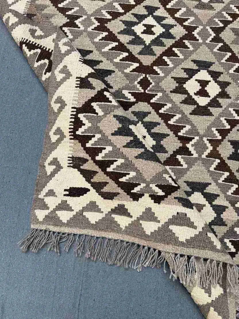 Folded view of small earthy-tone Kilim rug – handmade wool flatweave.