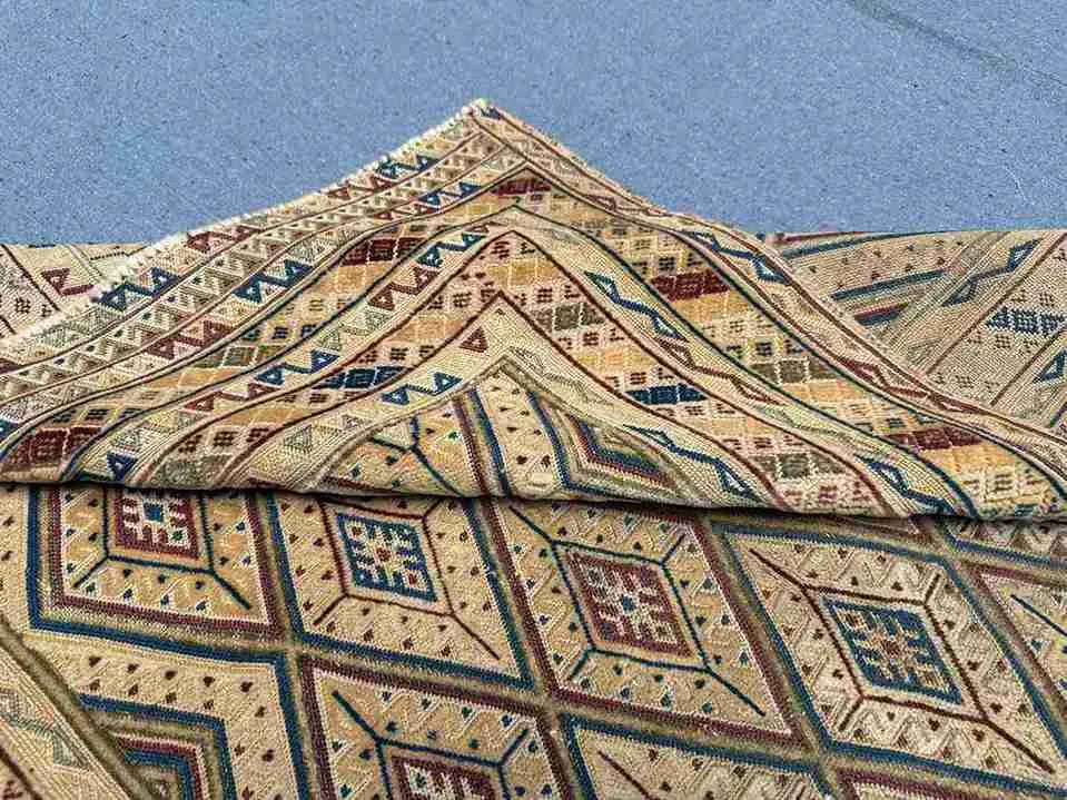 Side view of folded Turkish Afghan kilim rug showing wool edges