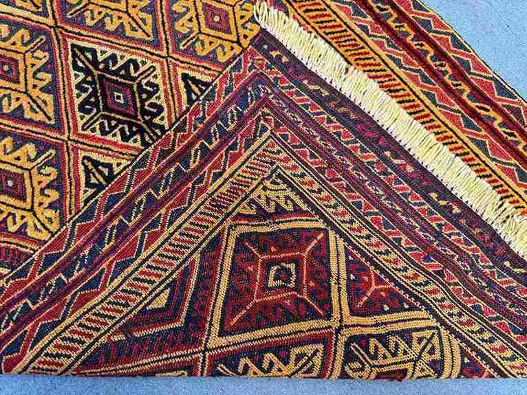 Folded tribal red and gold wool kilim rug with bohemian texture