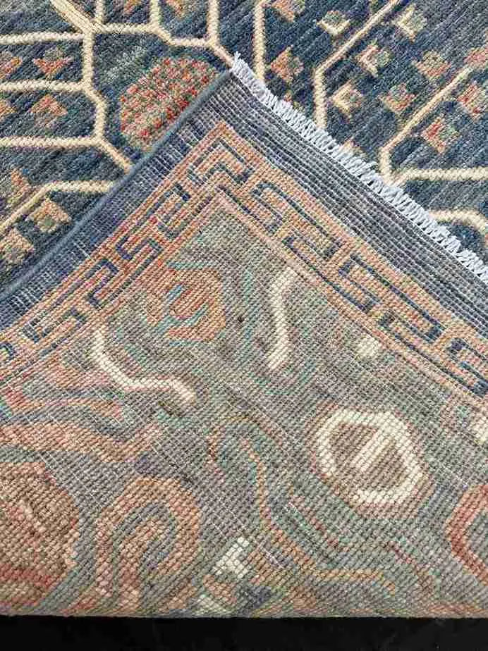 Folded 5x9 blue and beige Persian-style rug showing backside knotting