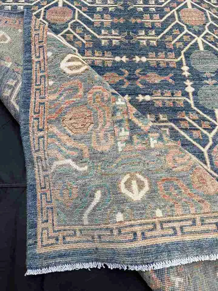 Folded 5x9 blue and beige Persian-style rug showing backside knotting