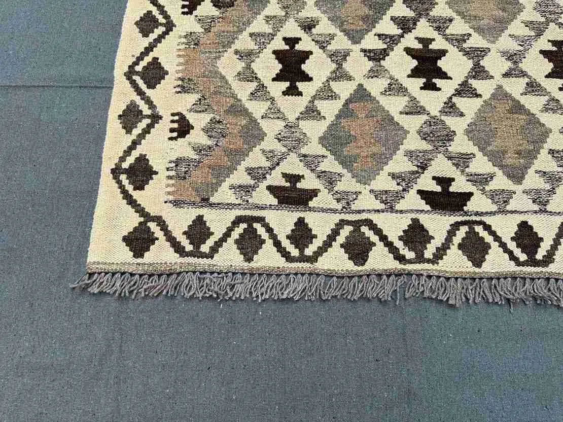 Corner detail of geometric Turkish Kilim rug – earthy tones in wool flatweave with knotted texture.