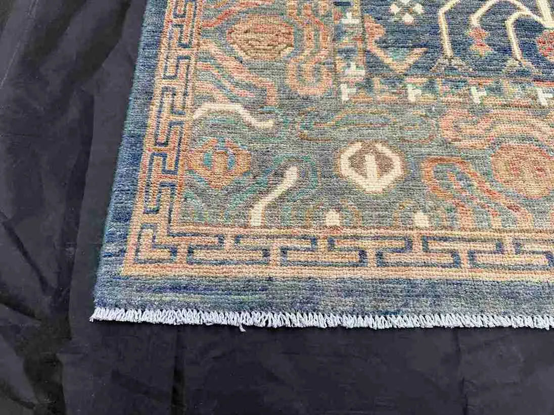 Corner detail of knotted 5x9 wool rug showing floral Persian design