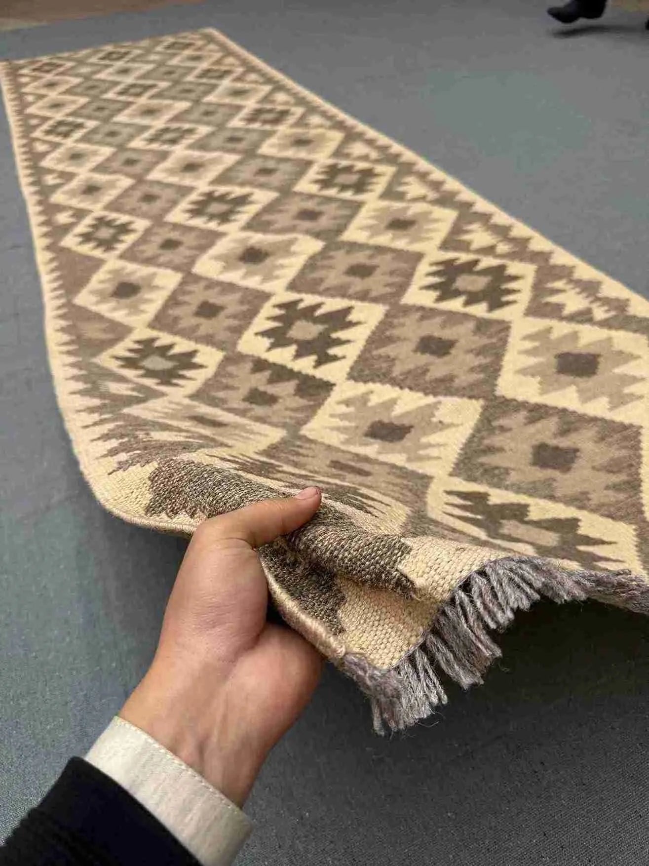 Handmade Turkish Kilim runner rug held in hands – front view showing texture and wool-silk detail.