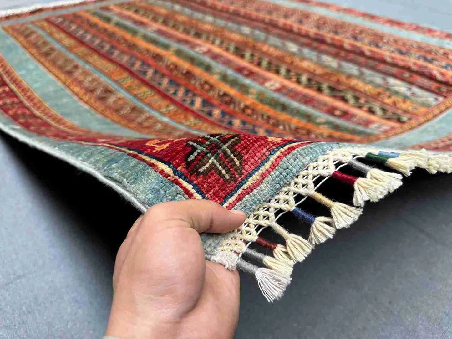 Wool striped Turkish kilim rug in hand, displaying texture and tribal motifs