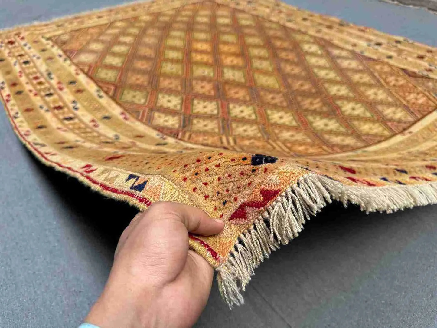 Handwoven 5x6.2 Afghan Turkish rug held in hands showing wool texture and beige, gold & brown tribal geometric design