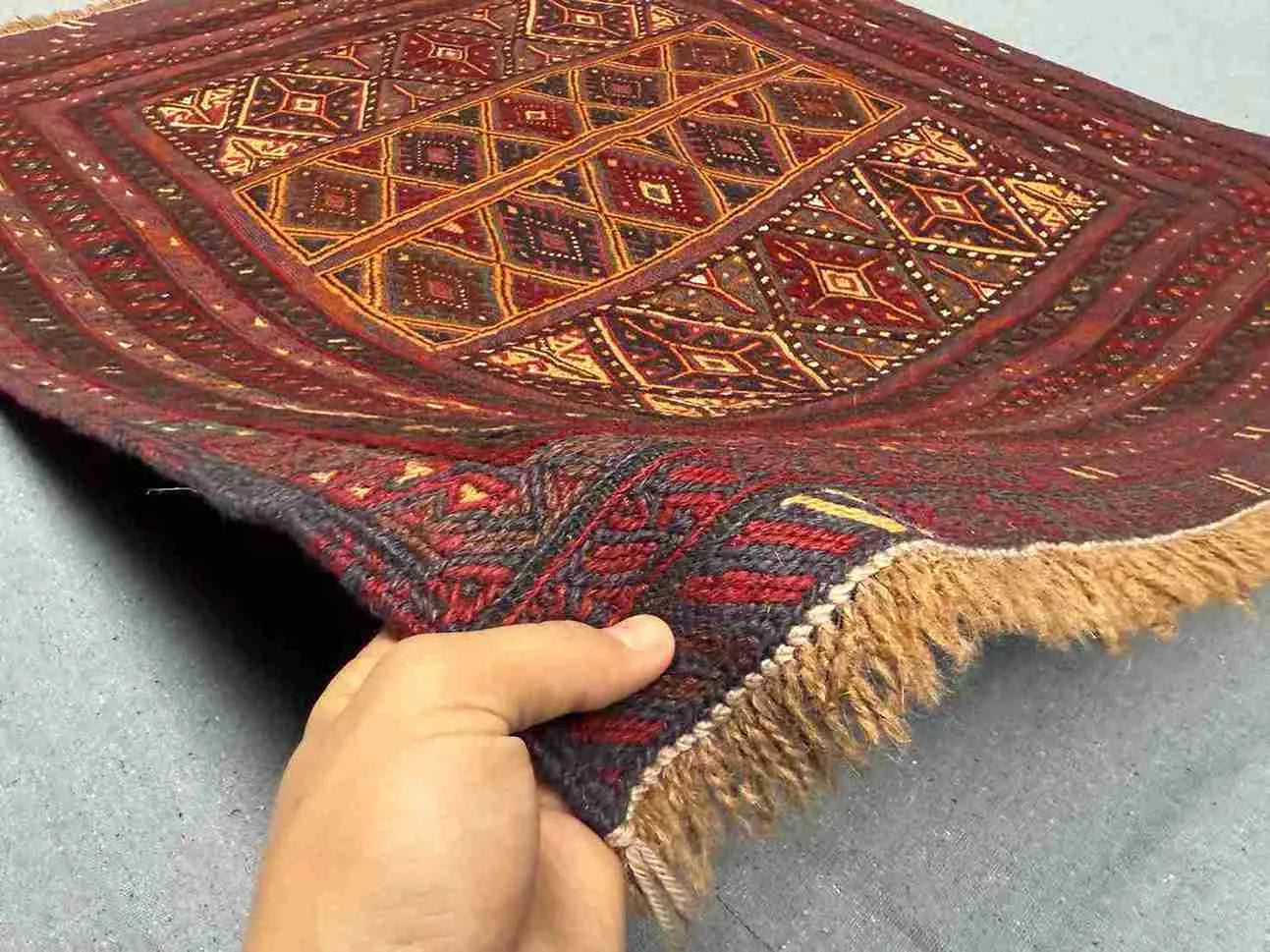 Handwoven 3.10x4.3 antique Afghan rug held in hands showing tribal wool weave and dark red tones
