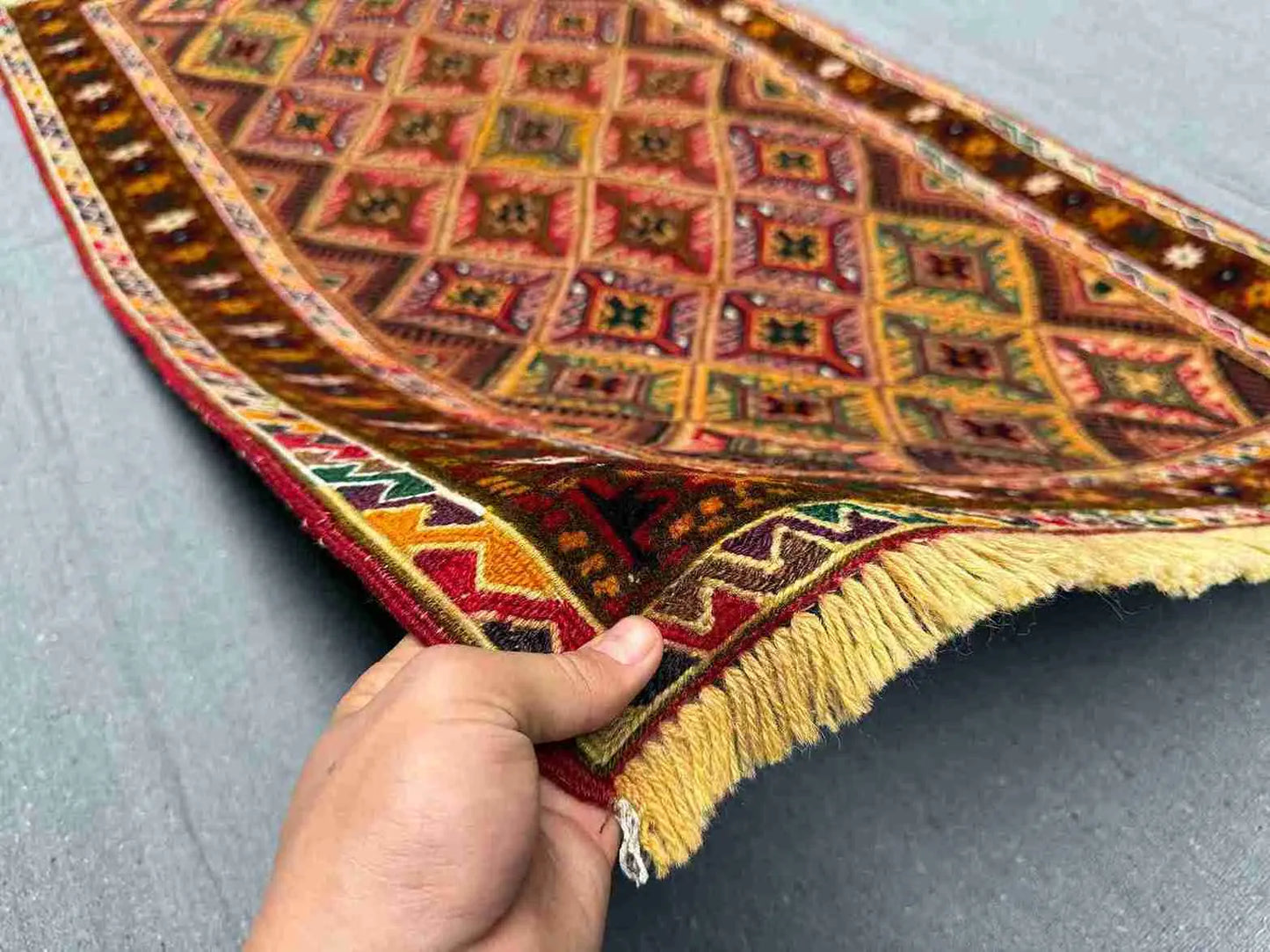 Handwoven 2.5x4.3 Turkish Afghan runner rug held in hands showing red, green and gold tribal patterns