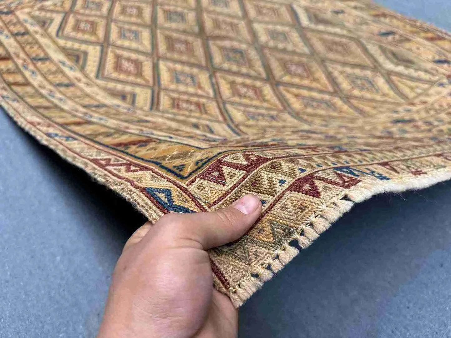 Handmade 3.2x4.3 Turkish Afghan kilim rug held in hands, showing tribal wool weave in beige, red, and blue