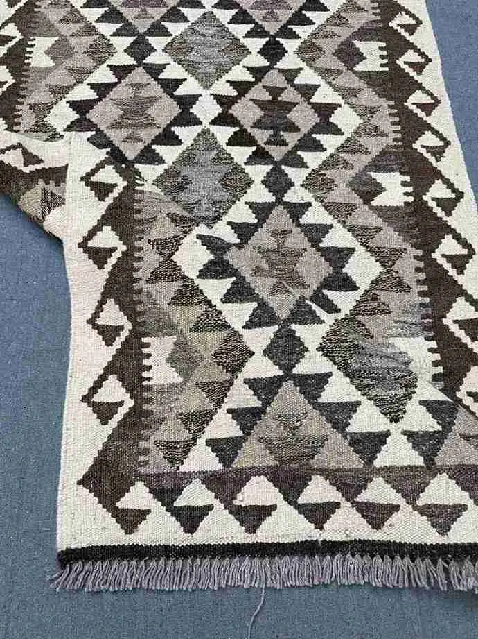Side view of folded Kilim wool runner – handmade carpet texture