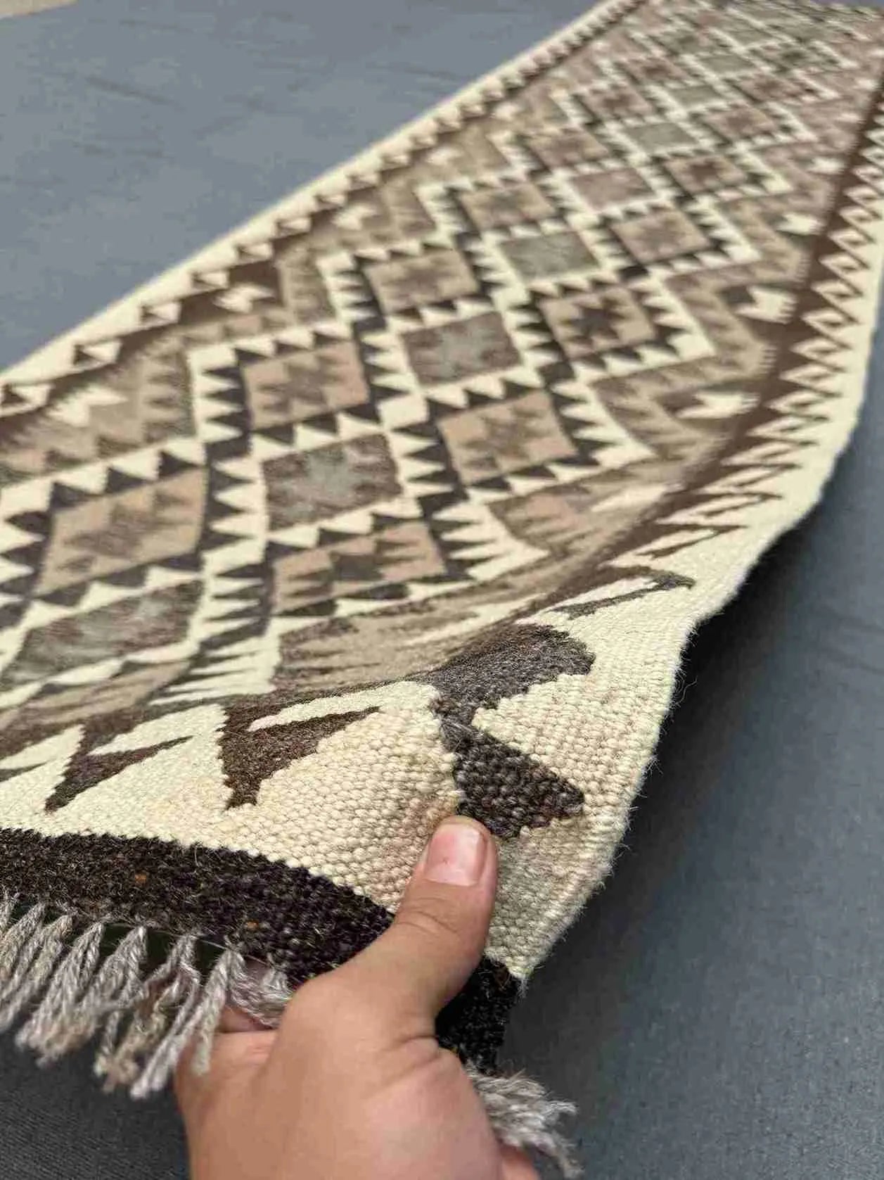 Handmade flatweave Kilim runner rug in hands – neutral beige tones