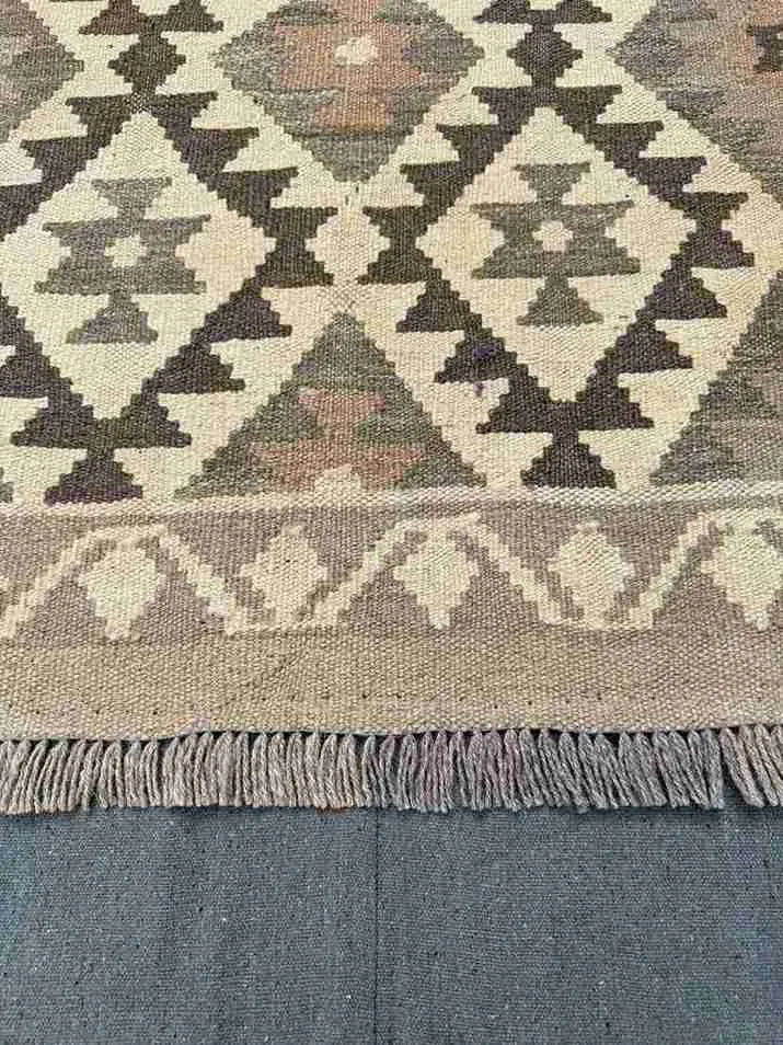 Close-up of knotted pattern on area rug – beige and brown geometric design.