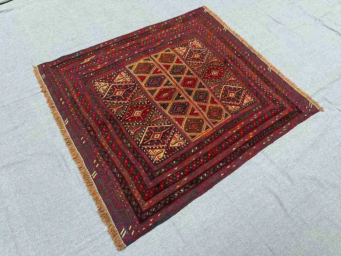 Nomadic oriental wool rug in red and brown displayed on wooden floor