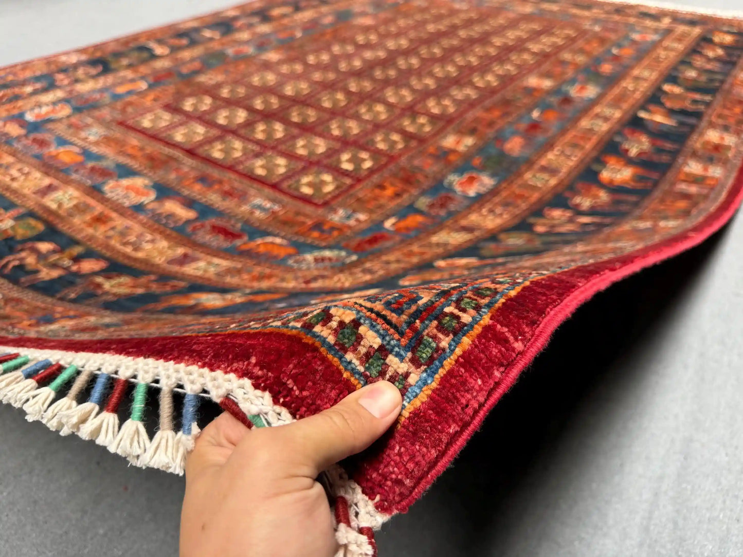 Authentic handmade Pazyryk rug shown in hands – red and blue tribal wool carpet