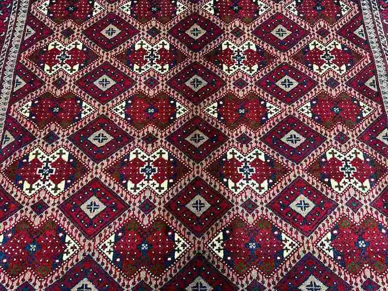 Close-up of red and beige Afghan wool silk rug with geometric pattern