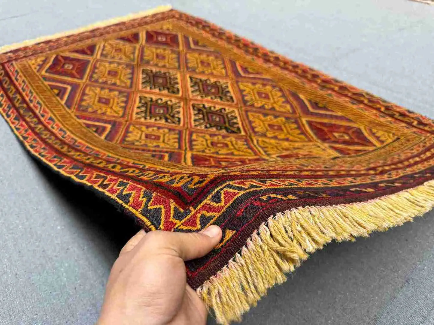 Handmade Persian Afghan kilim rug in hand showing wool weave texture