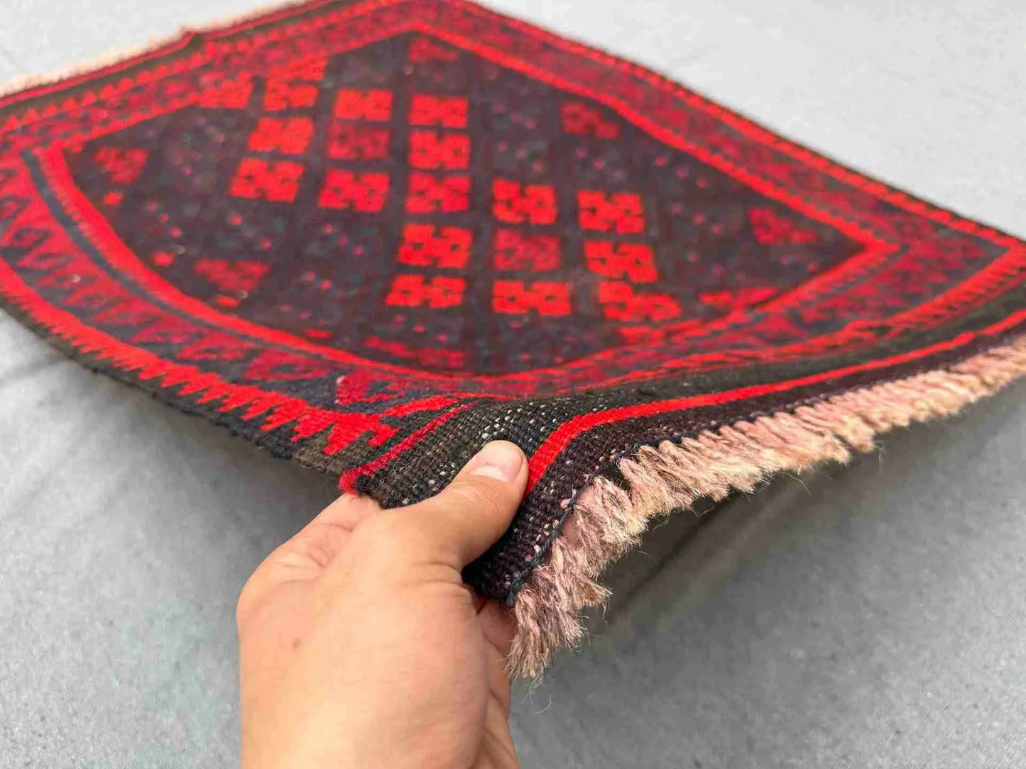 Handmade small red Kilim rug held in hands – geometric wool flatweave with traditional knotted design.