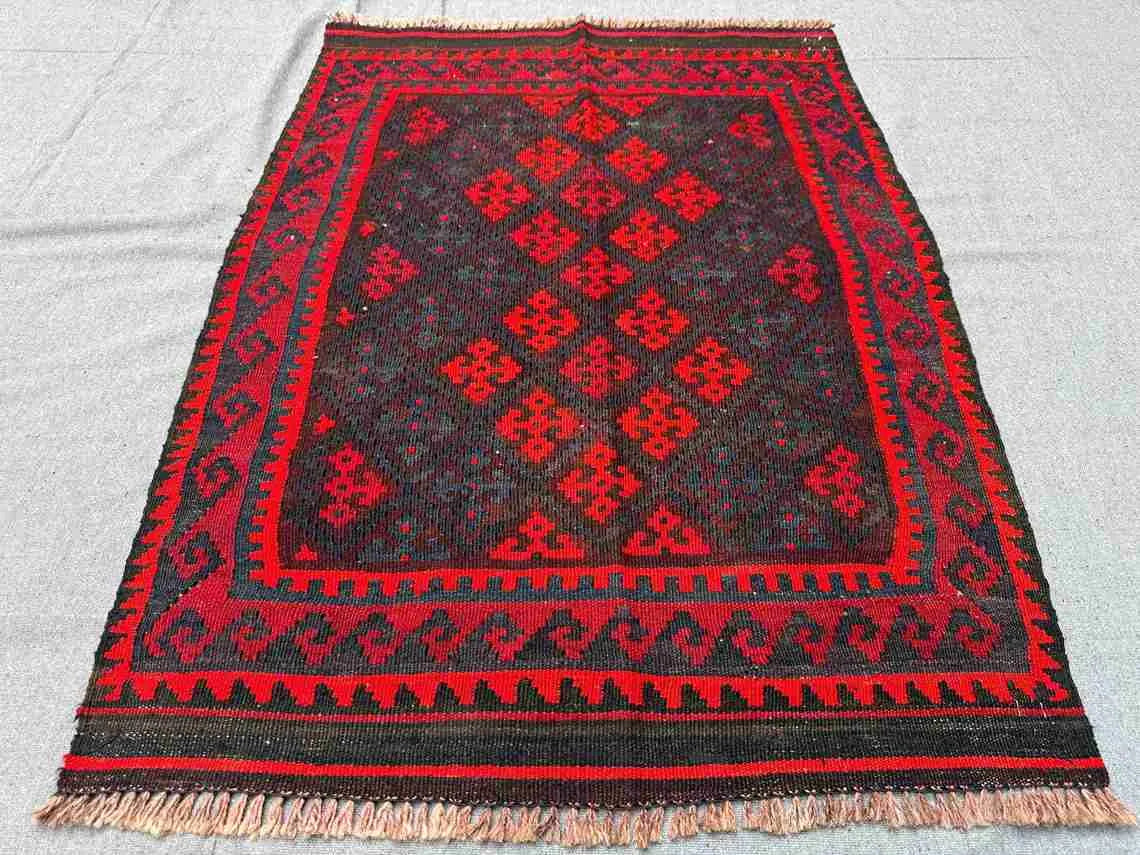Vintage red Kilim rug displayed on floor – handmade small wool rug for rustic or boho decor.