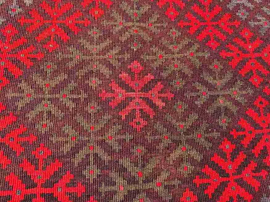 Texture close-up of red Afghan Kilim rug – handwoven geometric wool design.
