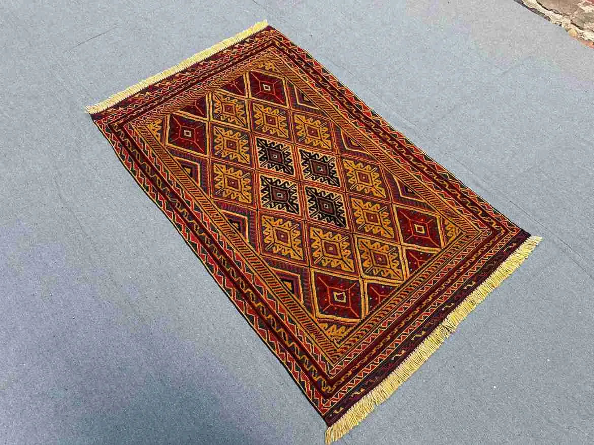 Traditional Afghan wool rug on floor with geometric tribal patterns