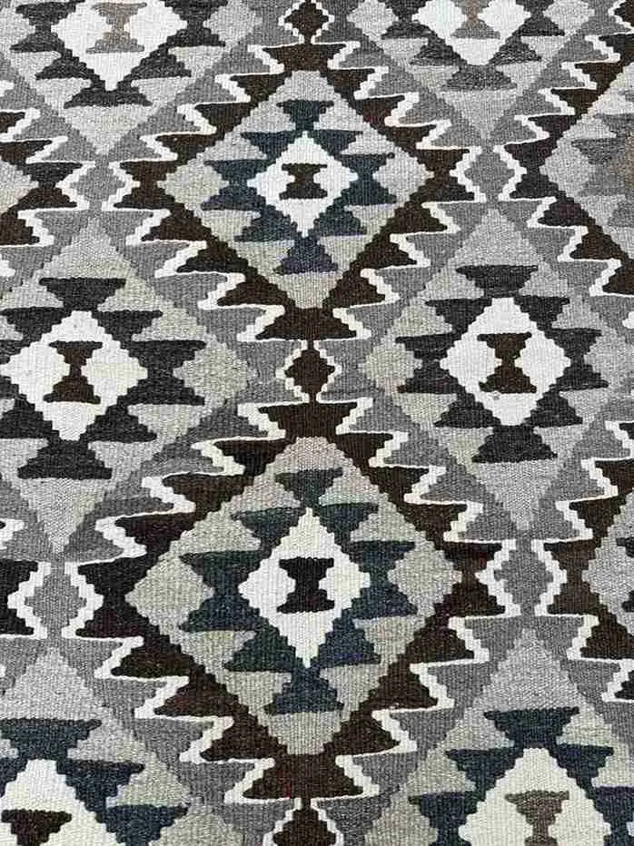 Close-up texture of traditional Turkish Kilim pattern – knotted wool rug in warm earth tones.