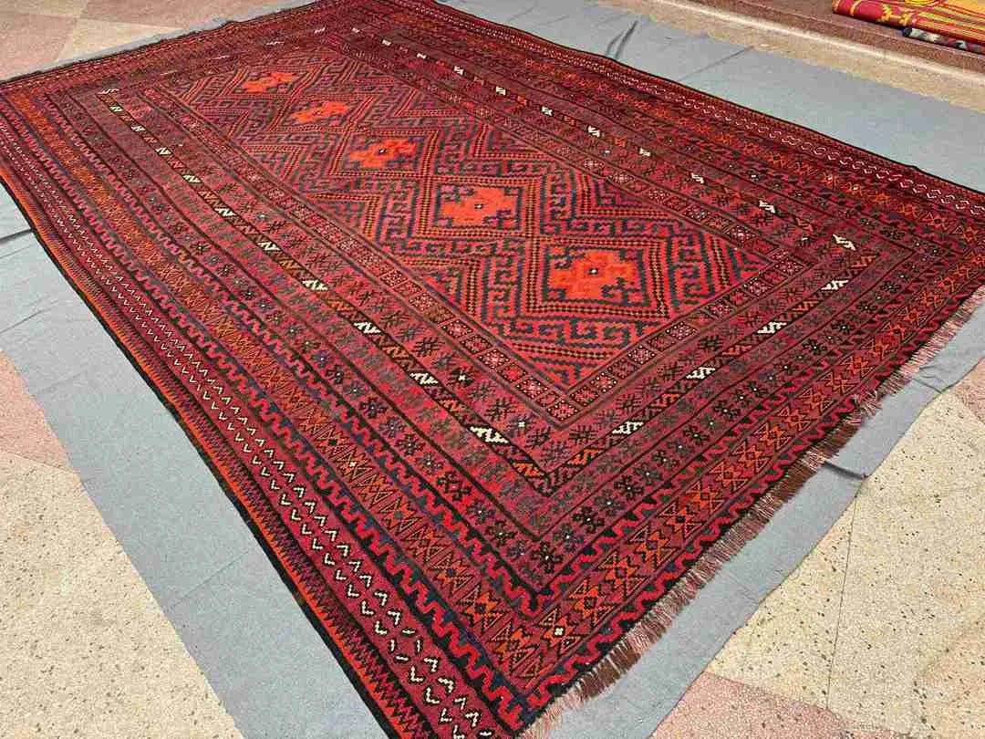 Handmade red and black Turkish Kilim rug styled on wooden floor – tribal geometric wool flatweave.